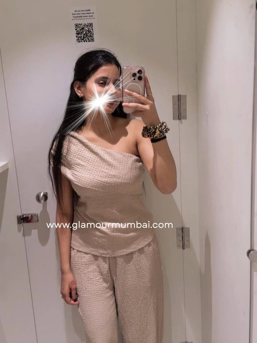 Pallavi premium Mumbai escort taking a mirror selfie indoors, wearing beige outfit near white door.