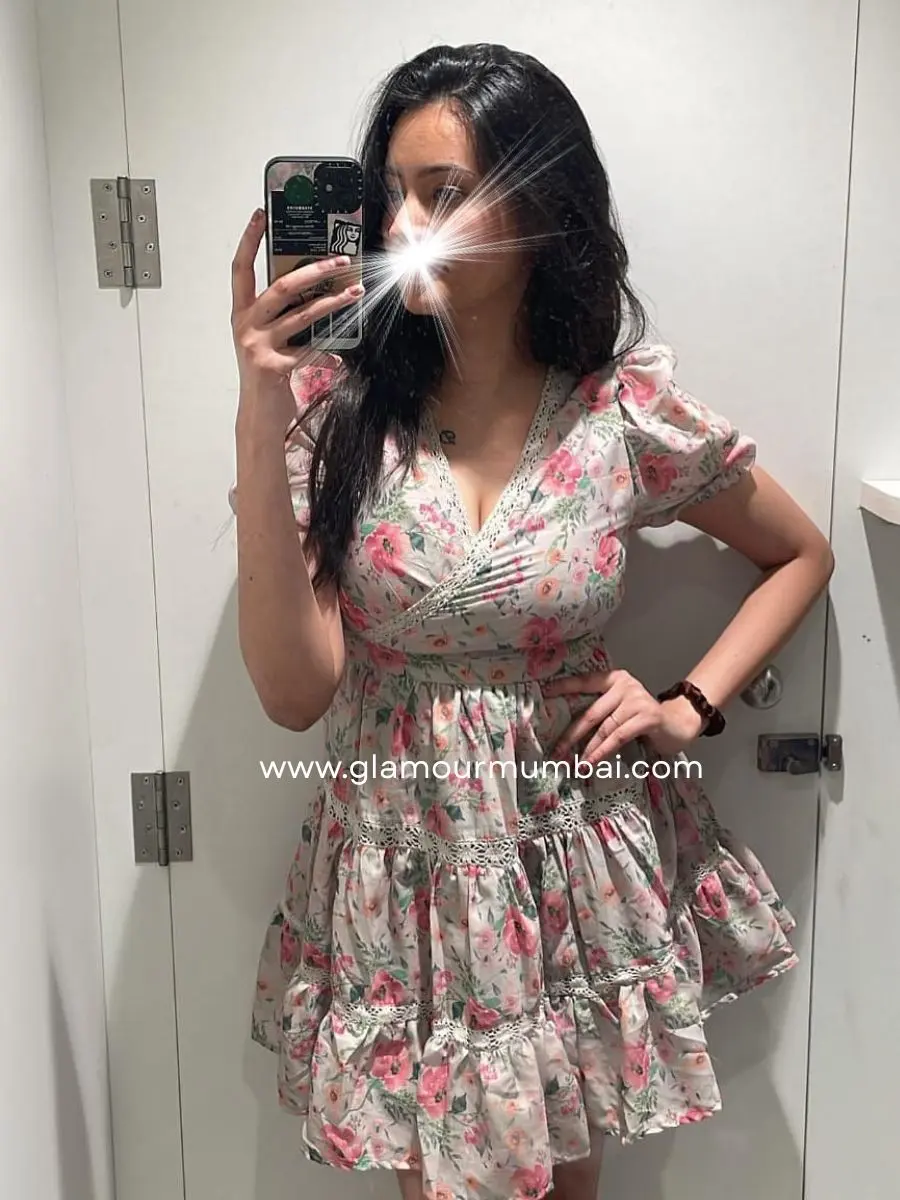 Pallavi verified escort in Mumbai taking a mirror selfie indoors, wearing a short floral dress and holding phone.
